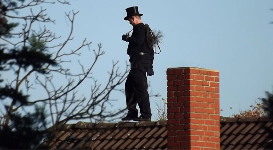 Na zdjęciu kominiarz chodzący po dachu