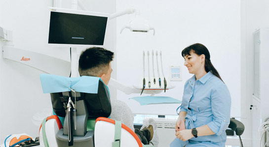 Na zdjęciu stomatolog rozmawia z pacjentem