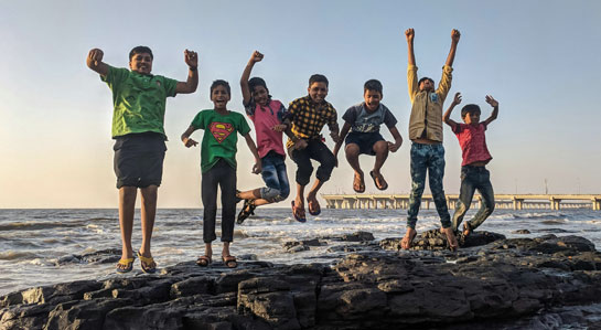 Na zdjęciu dzieci skaczące na morskiej skale