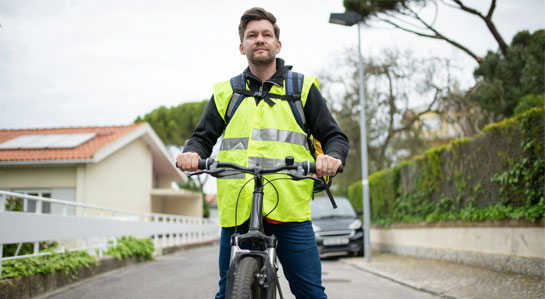 Rowerzysta ubrany w żółtą kamizelkę odblaskową.